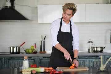 Asian cook in the kitchen prepares food in a cook suit