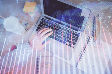 Double exposure of man's hands typing over computer keyboard and forex graph hologram drawing. Top view. Financial markets concept.