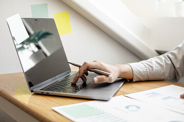 A close-up photo of a businessman typing on a laptop keyboard to examine the company's financial documents prepared by the Finance Department for a meeting with a business partner. Financial concept.