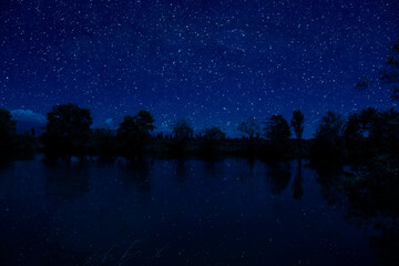 milky way over a lake at summer night with clear skies under moonlight.