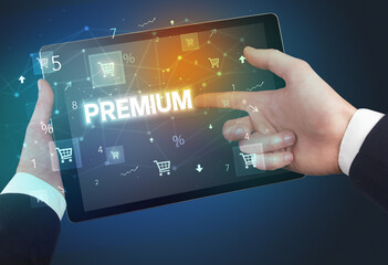 Close-up of a hand holding tablet with PREMIUM inscription, online shopping concept