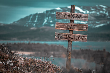 modern mass extinction text quote engraved on wooden signpost outdoors in landscape looking...