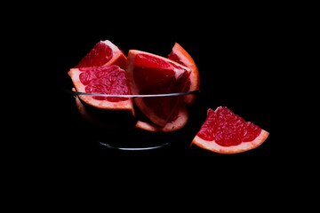 Red grapefruit parts in glass bowl on dark background. Closeup, copy space. Healthy diet concept