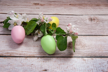 Easter composition. A blooming apple tree branch and colorful eggs close-up on a wooden background. Happy Easter Holidays.
