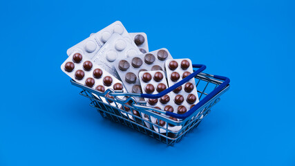 Shopping basket full of medical tablets in blister packs. Pharmacy costs and expenses of medical treatment concept