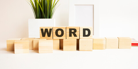 Wooden cubes with letters on a white table. The word is WORD. White background.