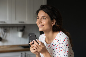 Fallen in love. Happy millennial woman texting with beloved man at social network using cell look aside dream of dating. Young lady motivated with good news at phone message visualize success in mind