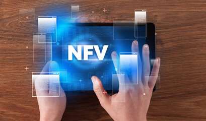 Close-up of a hand holding tablet with NFV abbreviation, modern technology concept
