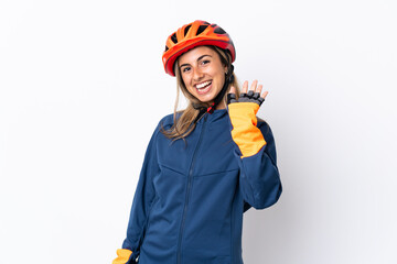 Young hispanic cyclist woman isolated on white background saluting with hand with happy expression
