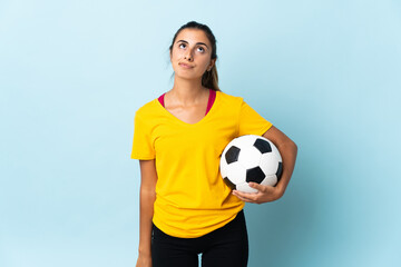 Young hispanic football player woman over isolated on blue background and looking up