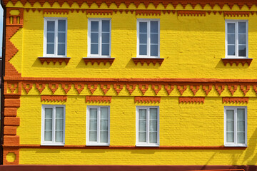 The facade of a old house made of brick painted in yellow and windows, beautiful bright background