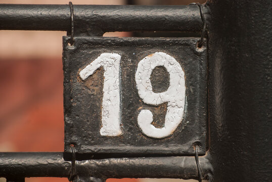 Old retro weathered cast iron plate with number 19 closeup