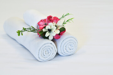 Clean white towels decorated with flowers ready for use on the bed in the hotel.