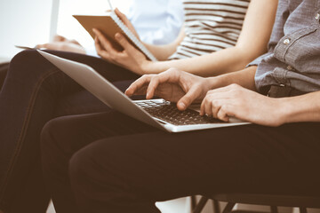 Group of casual dressed business people working at meeting or conference, close-up of hands. Businessman using laptop computer. Teamwork or coaching concept