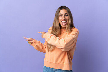 Fototapeta premium Young hispanic woman over isolated purple background surprised and pointing side