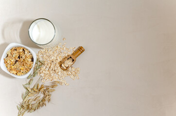 Creative layout of granola, muesli, milk in a glass on a beige background. The concept of a correct...