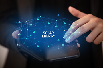 Businessman holding a foldable smartphone with SOLAR ENERGY inscription, new technology concept