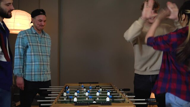 Group of young people having fun playing in table soccer at Home