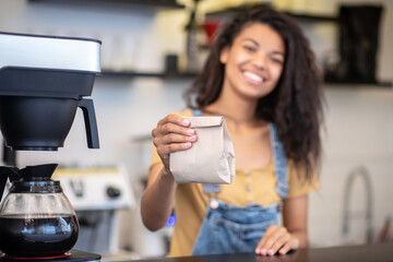 Small paper bag in outstretched hand of female barista