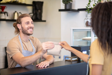 Man at counter giving package to woman