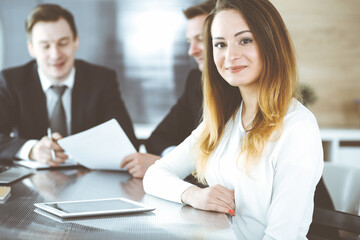 Fototapeta premium Business woman headshot at workplace in modern office. Unknown businesswoman sitting behind computer monitor. Young accountant or secretary looks good