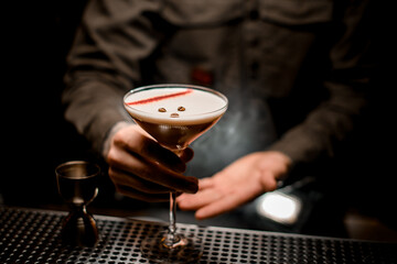 view on glass in male hands with espresso martini cocktail decorated with coffee beans