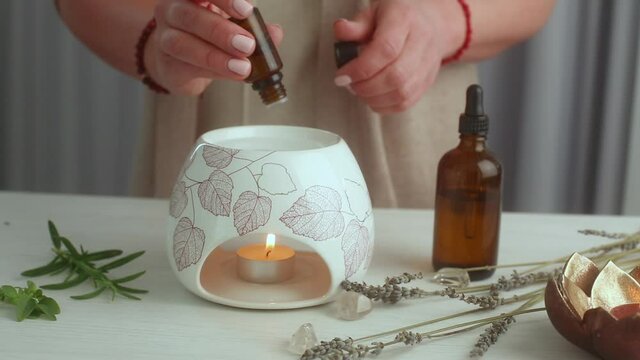 Home SPA concept. Woman preparing an aroma lamp and pouring oil