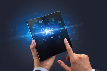 Businessman holding a foldable smartphone with CYBER CRIME inscription, cyber security concept