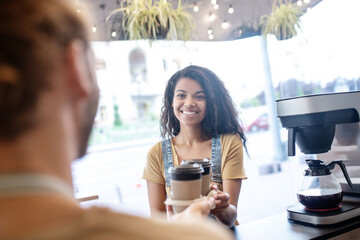 Woman picking up ordered takeaway coffee