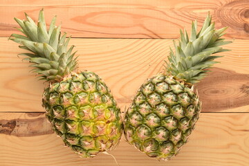 Two organic juicy pineapples on a wooden table, close-up, top view.