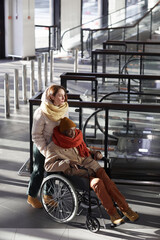 Obraz premium Vertical full length portrait of young woman assisting African American man in wheelchair at subway station, copy space