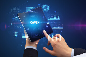 Businessman holding a foldable smartphone with CAPEX inscription, successful business concept