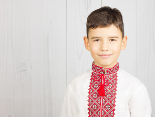 Handsome little boy in Ukrainian national costume on white wood background