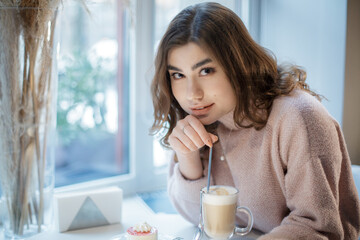 Pretty young woman sitting in the cafe and look at the camera.