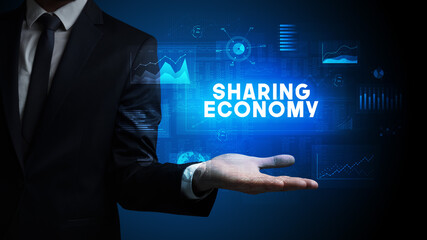Hand of Businessman holding SHARING ECONOMY inscription, business success concept