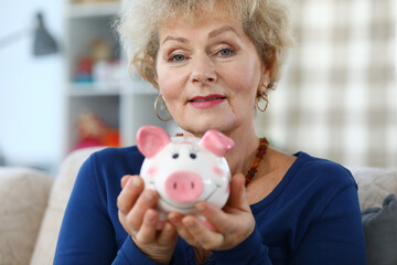 Portrait of woman with pink piggy bank in her hands. Saving money concept