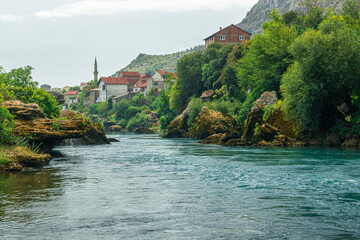 Neretva river in Mostar town with old mosque and clear turquoise water. summer landscape