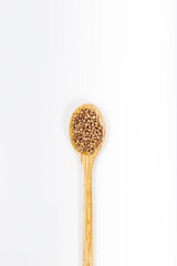 Coriander seeds in wooden spoon isolated on white background. Top view.