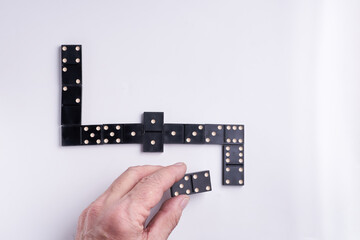 Macro image of dominos on a leather table in the middle of a game with hand placing a tile