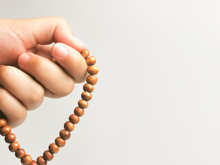 Selective focus close up image  hand of muslim woman holding a prayer beads isolated on white background with copy space. 