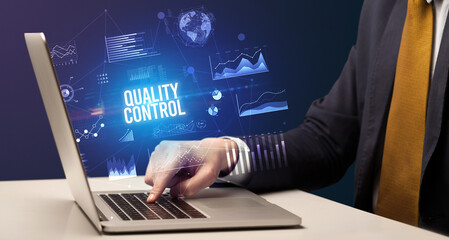 Businessman working on laptop with QUALITY CONTROL inscription, new business concept