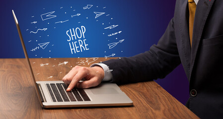 Businessman working on laptop with SHOP HERE inscription, online shopping concept