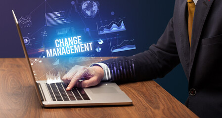 Businessman working on laptop with CHANGE MANAGEMENT inscription, new business concept