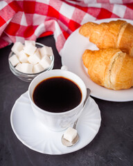 delicious fresh croissant and cup of coffee on a dark stone rustic background