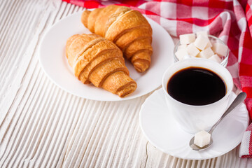 delicious fresh croissant and cup of coffee on a white wooden rustic background