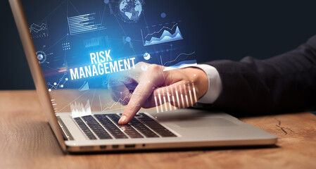 Businessman working on laptop with RISK MANAGEMENT inscription, new business concept