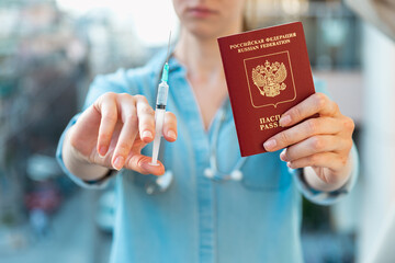 Woman holding medical injection syringe and passport towards the camera. Selective focus