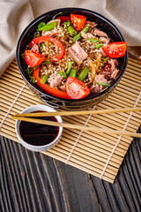 delicious glass noodles with tuna and vegetables on a dark wooden rustic background