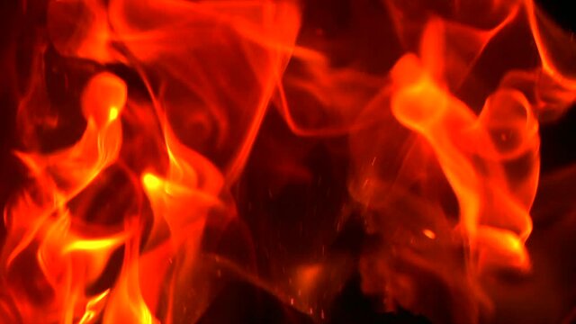 Burning fire. Fire flames with flying sparks background. Firestorm texture, shot of flying fire sparks in the air. Burning bonfire over dark night backdrop. Slow motion 4K UHD