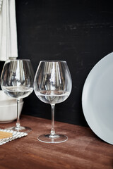 two glass wine glasses with water on a wooden table